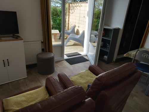 - un salon avec deux fauteuils en cuir et une télévision dans l'établissement Gîte la Beautėe, à Hermanville-sur-Mer