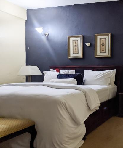 a bedroom with a large bed with a blue wall at Savoy Palmz in Limbe