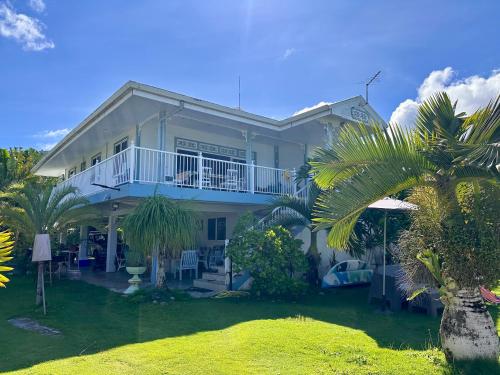 a large white house with a balcony and palm trees at Meri Lodge Huahine « ROOM OF MARTA » in Fare