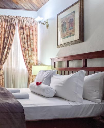 Un dormitorio con una cama con almohadas blancas y una ventana en Savoy Palmz en Limbe