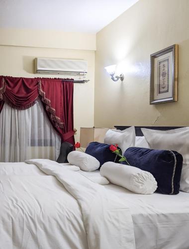 Una cama con sábanas blancas y almohadas azules. en Savoy Palmz en Limbe