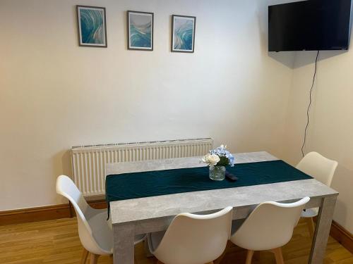 tavolo da pranzo con sedie bianche e televisore di The Anglesea - 8 Bedroom with Parking a Southampton