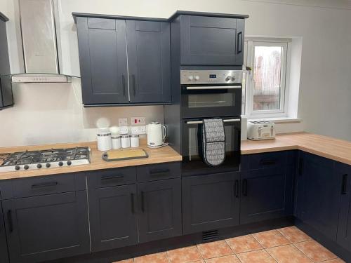 una cucina con armadi neri e piano cottura. di The Anglesea - 8 Bedroom with Parking a Southampton