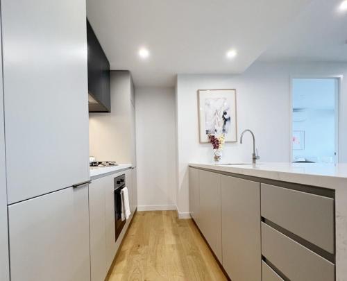 a kitchen with white cabinets and a sink at Myka Home New Apartment in Box Hill YS4A in Box Hill