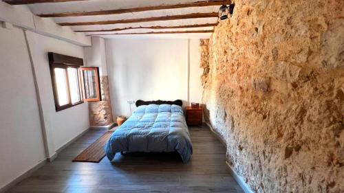 Cama en habitación con pared de piedra en Casa Cueva Toni, en Alcalá del Júcar