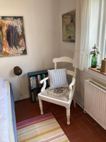 a bedroom with a white chair with a pillow on it at Glædegården -Glaede Landhof- 12 beds! in Frøstrup