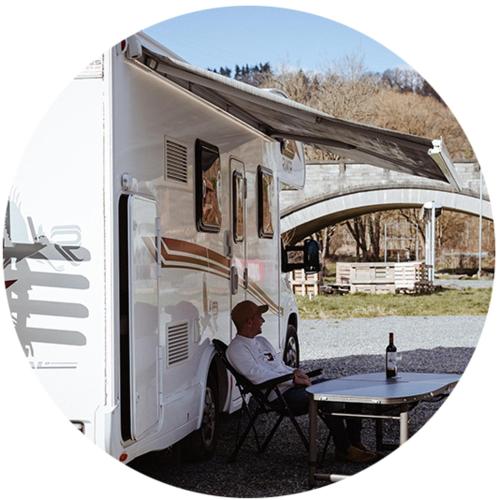 a man sitting at a table in front of an rv at the green paradise in Celles