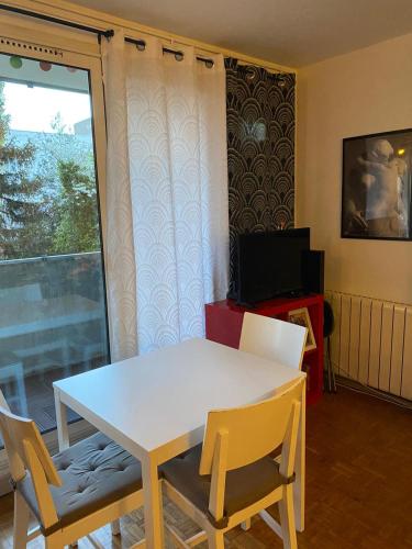 une salle à manger avec une table et des chaises blanches ainsi qu'une fenêtre dans l'établissement Tout confort, à Les Pavillons-sous-Bois