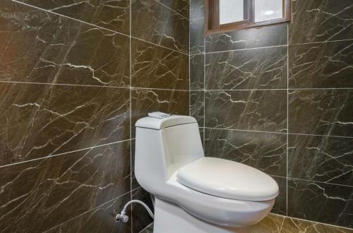 a white toilet in a bathroom with marble walls at Frida's Inn 丽江梦之旅观景客栈 in Lijiang