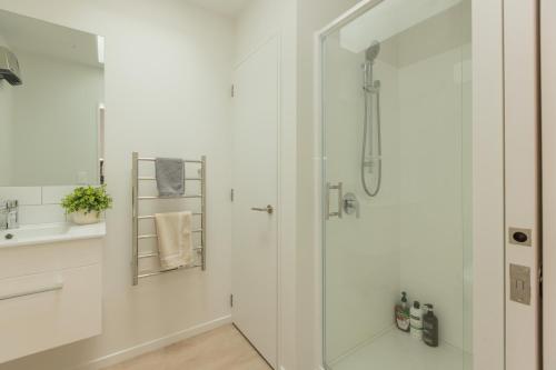 baño blanco con ducha y lavamanos en Addington SOHO Two Bedroom Townhouse en Christchurch