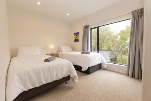 1 dormitorio con 2 camas y ventana grande en Addington SOHO Two Bedroom Townhouse en Christchurch