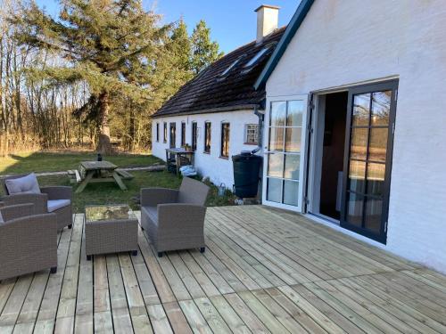 a deck with chairs and a table and a building at Glædegården -Glaede Landhof- 12 beds! in Frøstrup