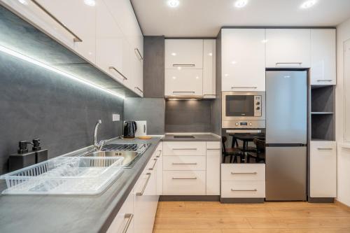 a kitchen with white cabinets and stainless steel appliances at Harmony Suite in Sofia