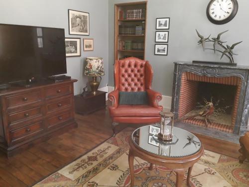 sala de estar con TV, silla y chimenea en La Belle Epoque en Époisses