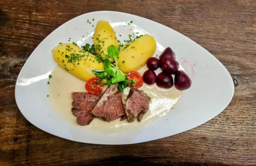 talerz żywności z mięsem i owocami na stole w obiekcie Pension & Biergarten Spreewaldhof Leipe w mieście Leipe