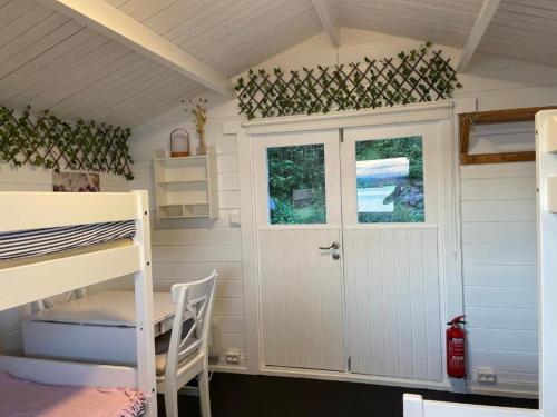 a small room with a bunk bed and a door at Nice Apartment with1 bedroom Separate living room with a sofa bed and a tiny kitchen a bathroom located in Nordstrand near by the Sea for 3 guests with a garden and grill 5 extra guests with extra cost in the cabin with sea view just outside the apartment in Oslo