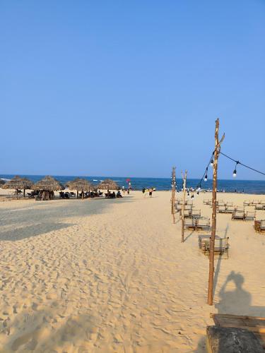 a beach with some chairs and umbrellas and the ocean at View Nhat Le Beach Hotel in Dong Hoi