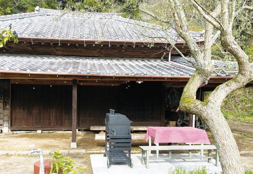 a table and a bench in front of a building at 大自然に囲まれた築120年の隠れ家古民家で里山リラクゼーション in Isumi