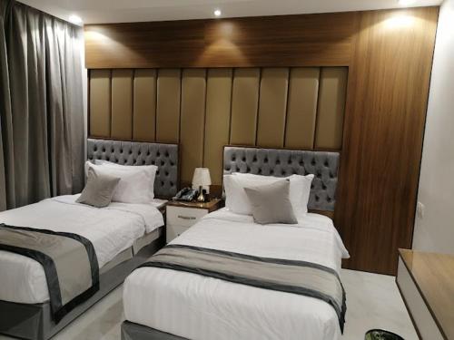 a bedroom with two beds with white sheets at شقق درة العريش لشقق المخدومة in Jazan