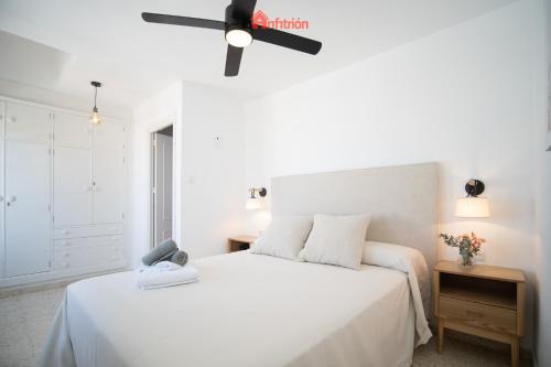 Schlafzimmer mit einem weißen Bett und einem Deckenventilator in der Unterkunft El Anfitrión - Casa Dunas in Sanlúcar de Barrameda