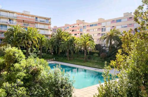une piscine devant un immeuble avec des palmiers dans l'établissement Design loft Studio climatisé parking et piscine, à Vallauris