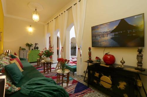 sala de estar con sofá verde y TV de pantalla plana en Dar Didifa en Marrakech