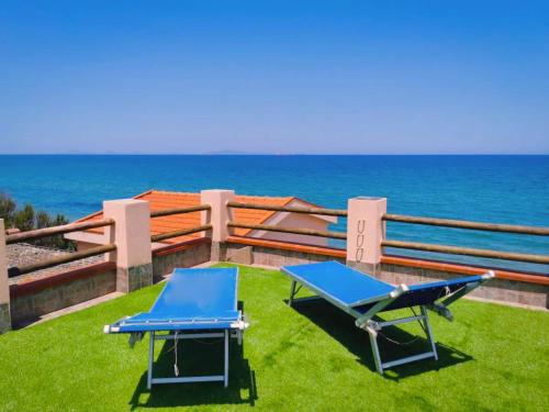 dos sillas azules y una mesa en la hierba cerca del océano en Platasun Terrace - with a breathtaking view, en Platamona