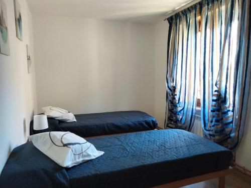 a room with two beds with blue sheets and a window at Maison Dayné - DimoraAlpina in Introd