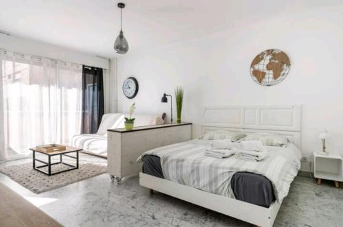 a white bedroom with a bed and a clock on the wall at Design loft Studio climatisé parking et piscine in Vallauris