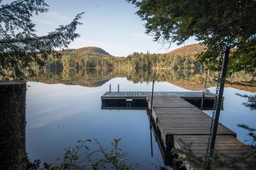 a dock on a lake with mountains in the background at Les Refuges Perchés Mont-Tremblant in Saint-Faustin