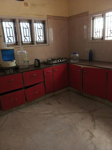an empty kitchen with red cabinets and windows at Shree Eco Stay in Chennai