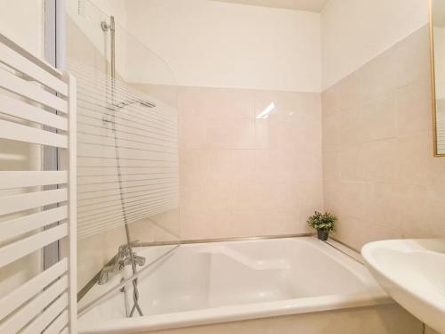 une salle de bain blanche avec une baignoire et un lavabo dans l'établissement Appartement 5 couchages + jardin à 150m des plages, à Saint-Raphaël