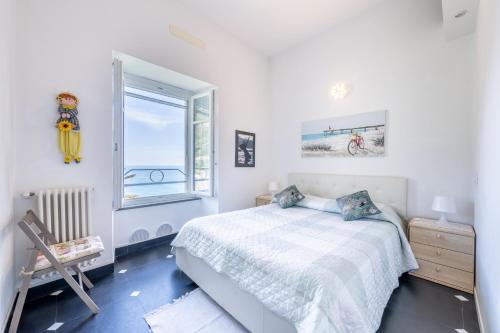 a white bedroom with a bed and a window at La Coccinelle - Superb Views in Corniglia