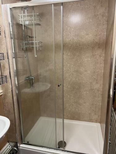 a shower with a glass door in a bathroom at Spacious one bedroom flat w/ parking in Walsall