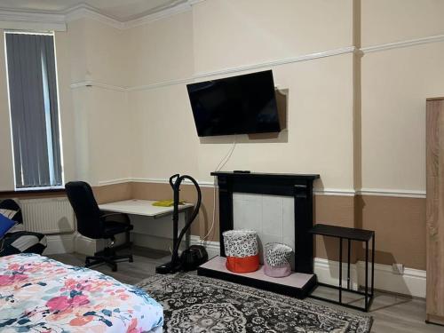 Habitación con cama, escritorio y TV. en Spacious one bedroom flat w/ parking, en Walsall