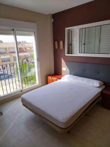 - une chambre avec un grand lit et 2 fenêtres dans l'établissement Casa adosada en Daimus solo para familias, à Daimús