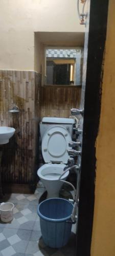 een badkamer met een toilet en een blauwe emmer bij Rajs Lodging & Fooding (Guest House) in Calcutta