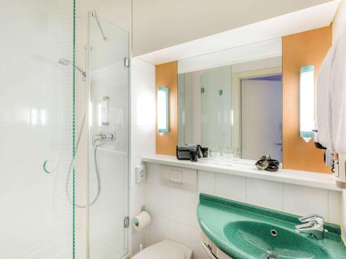 ein Badezimmer mit einem grünen Waschbecken und einer Dusche in der Unterkunft ibis Ulm City in Ulm