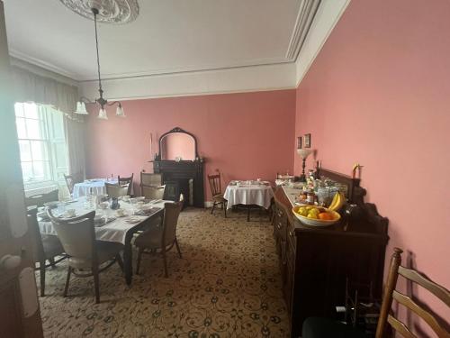 a dining room with pink walls and tables and chairs at Ashmore House in Cashel