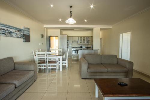 een woonkamer met banken en een tafel en een keuken bij Saints View Resort Unit 15 in Uvongo Beach