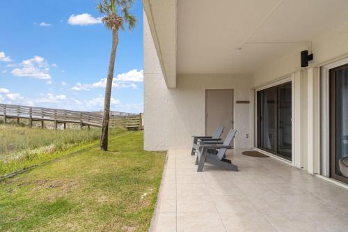 a patio with two chairs and a palm tree at Shipwatch B101 in Perdido Key