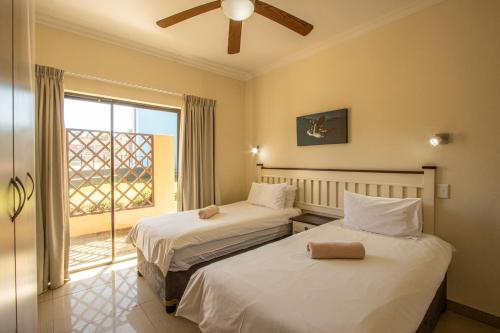 two beds in a room with a window at Saints View Resort Unit 15 in Uvongo Beach