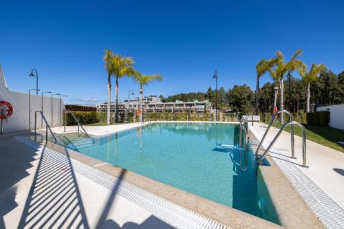 una gran piscina con árboles y palmeras en Luxury House Chaparral Golf E70 by AORA STAY, en La Cala de Mijas