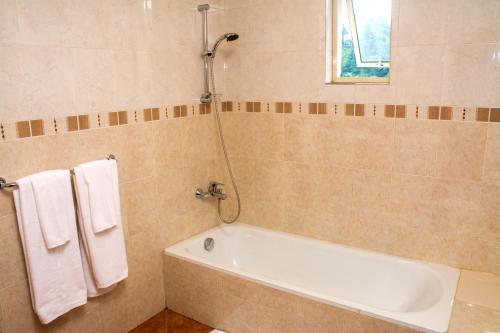 a bathroom with a tub and a shower and towels at Hotel Lakefield in Kandy