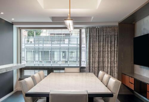 a dining room with a table and chairs and a large window at Conrad New York Downtown in New York