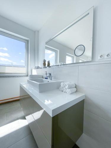 a white bathroom with a sink and a mirror at Ferienwohnung auf dem Hof Postma in Lambrechtshagen