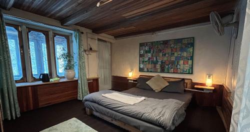 a bedroom with a bed and two windows at Aloha Riverside in Kasol