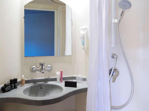 a bathroom with a sink and a shower with a mirror at ibis budget Albi Terssac in Terssac