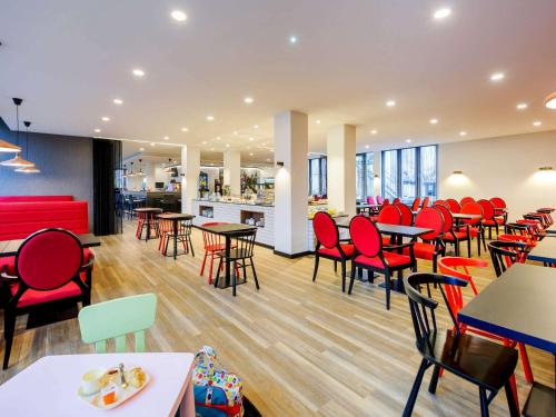 a restaurant with red chairs and tables and a cafeteria at ibis Styles Halle in Halle an der Saale