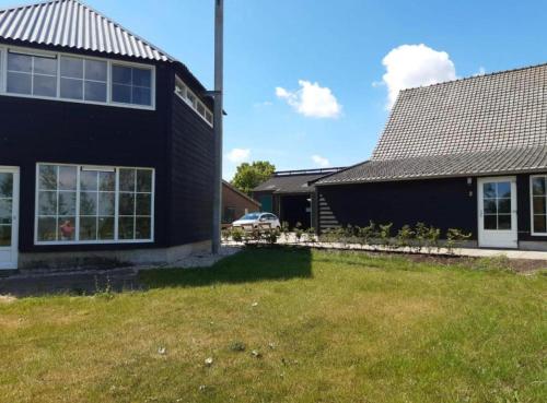 a black house with a yard in front of it at Blossom Barn Lodges in Oudewater